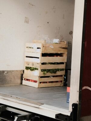 A wooden crate with fresh vegetables loaded inside a delivery truck, ready for transportation.